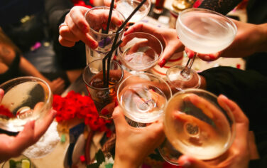 Picture of clinking glasses with alcohol and toasting, celebrating the fun things to do in Melbourne