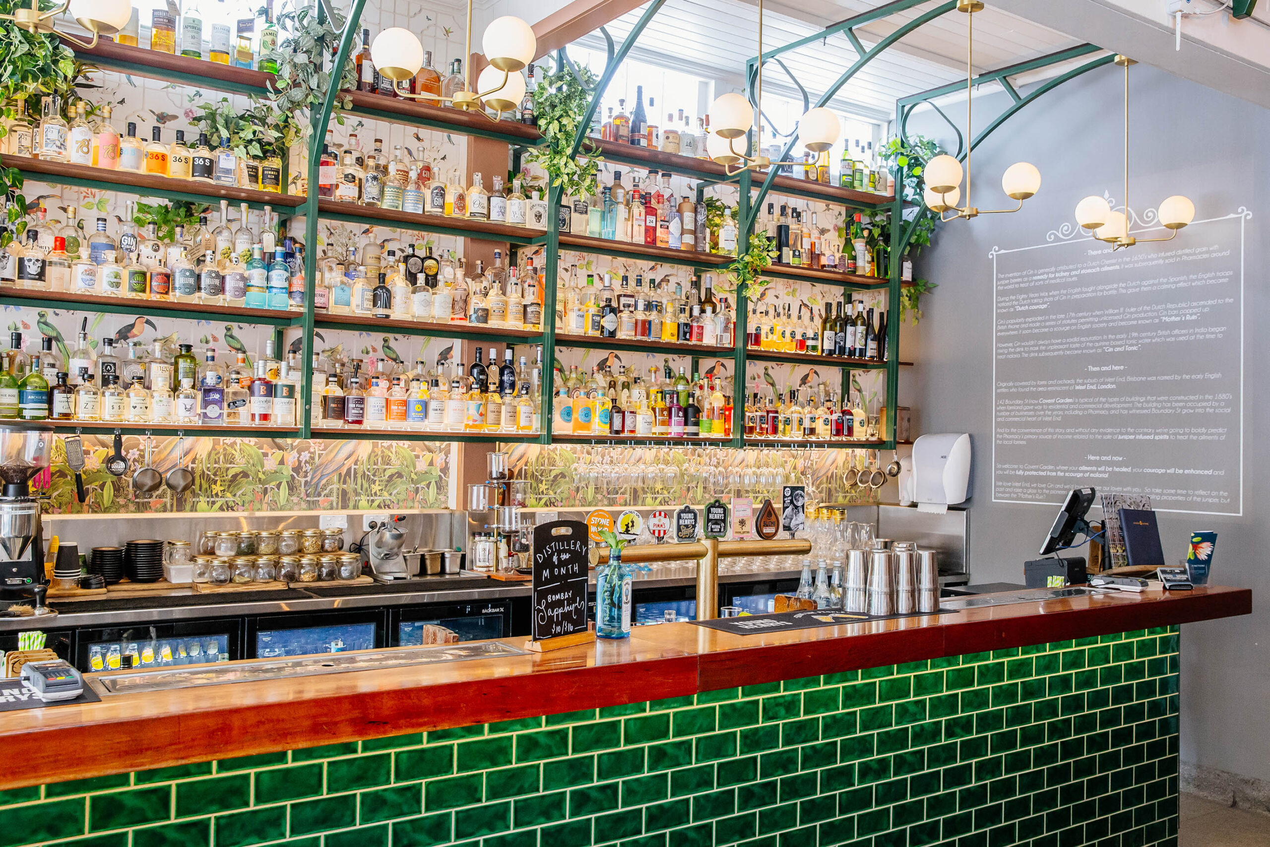 Covent Garden West End image showing a bar with green tiles and a red top with hundreds of spirit bottles behind to order from