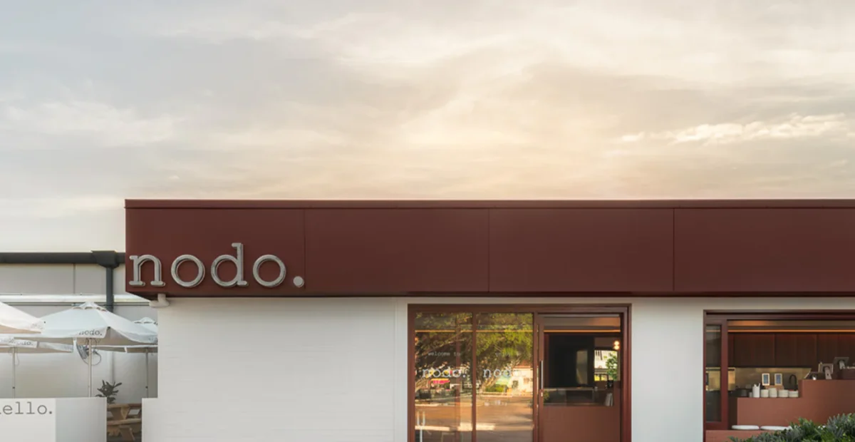 Image shows a sun setting over a cafe which is Nodo Everton Park with empty car parks out the front