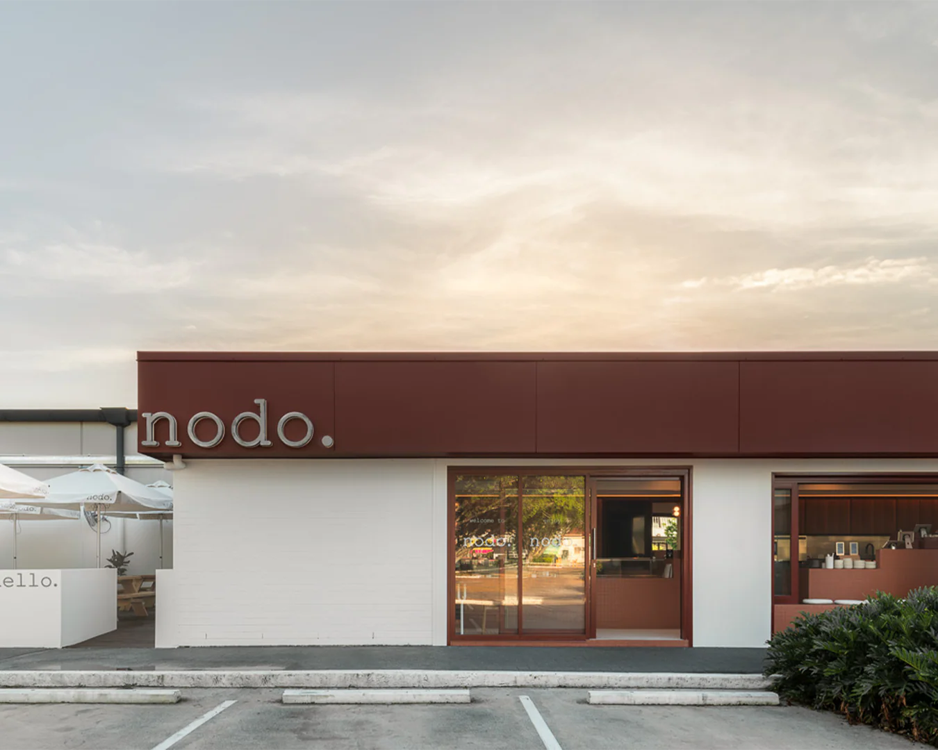 Image shows a sun setting over a cafe which is Nodo Everton Park with empty car parks out the front