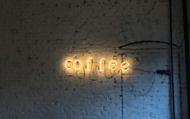 Picture of a neon light that says Coffee on a white brick wall at a laneway coffee house in Brisbane